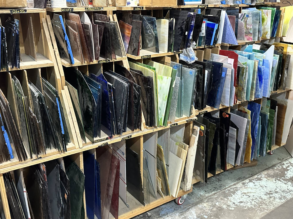 Racks of smaller pieces of stained glass arranged by style and color